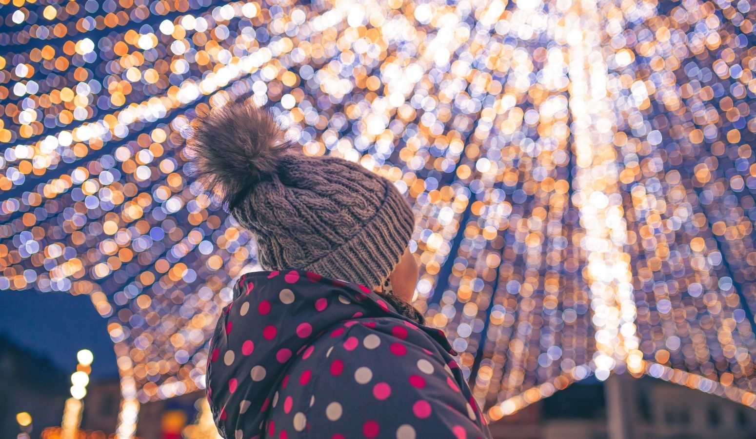 Puestos de madera iluminados y una gran noria en los mercadillos navideños de Flandes, ideal para visitar en familia durante el Puente de Diciembre.